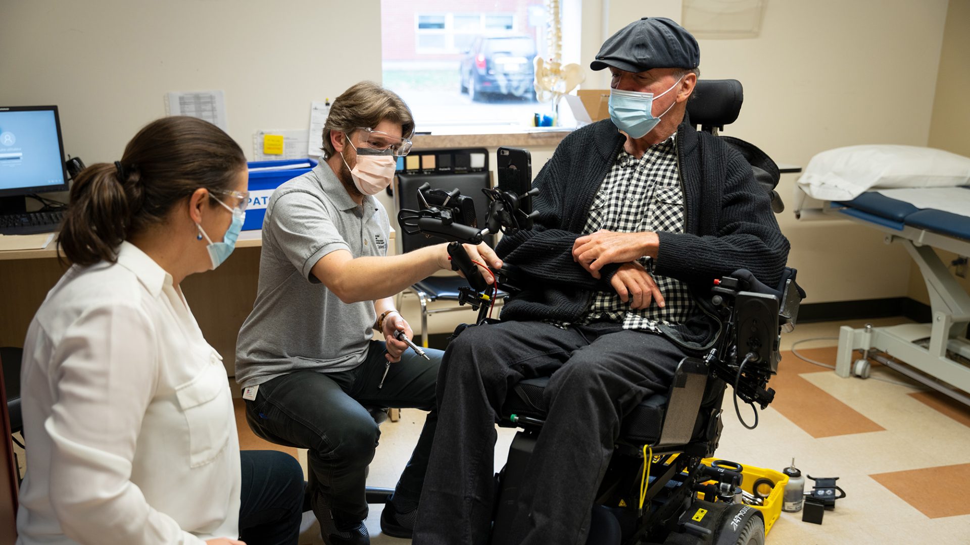 Deux professionnels de la santé ajuste le fauteuil électrique d'un usager