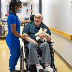 Une infirmière et un patient en chaise roulante qui se promènent dans le corridor d'un CHSLD.