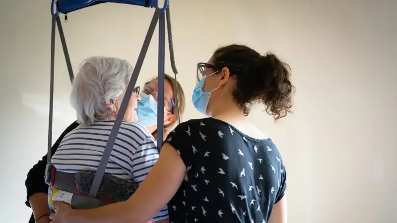 Deux spécialistes de la réadaptation qui aide une personne âgée à se déplacer avec un harnais